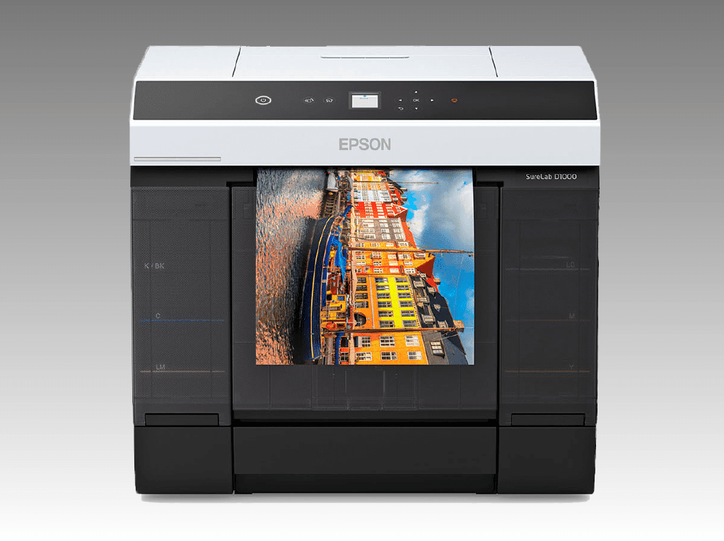 The Epson Surelab SL-D1000 is a compact printer that can print up to 460 6×4″ prints in an hour. It comes with a new 1.44" LCD screen and built-in wireless connectivity. The Epson SureLab SL-D1000/D1000A, Epson SureLab SL-D1030, Epson SureLab SL-D1060, and Epson SureLab SL-D1070/D1070SE/D1070DE Dry Lab Inkjet printers can significantly increase productivity, and the Duplex Feeder allows for double-sided printing. Orders from kiosks can be sent directly to the Epson SureLab for easy editing, modification, and printing using BlueFX Epson RIP software. BlueFX offers professional RIP software for the Epson SureLab D1000 Series printer to improve photo printing efficiency. Our software includes features such as hot folders, support for multiple file formats, photo packages, ICC profiles, high volume printing, drag and drop functionality, auto print sizing, and darkroom integration. Enhance your photo printing efficiency with BlueFX today. [en]; L'Epson Surelab SL-D1000 est une petite imprimante qui offre une vitesse d'impression allant jusqu'à 460 impressions 6×4″/heure, un nouvel écran LCD de 1,44" et une connectivité sans fil intégrée. Les imprimantes à jet d'encre de laboratoire sec Epson SureLab SL-D1000/D1000A, Epson SureLab SL-D1030, Epson SureLab SL-D1060, Epson SureLab SL-D1070/D1070SE/D1070DE offrent une productivité considérablement améliorée et le Duplex Feeder offre une polyvalence supplémentaire avec l'impression recto-verso. Les commandes des banques de kiosques sont directement traitées sur l'Epson SureLab, ce qui permet une approbation, une édition, une modification et une impression faciles avec le logiciel BlueFX Epson RIP. Si vous souhaitez optimiser votre impression photo, BlueFX propose un logiciel RIP professionnel pour l'imprimante Epson SureLab D1000 Series. Notre logiciel comprend des fonctionnalités telles que des « dossiers actifs », plusieurs formats de fichier, des paquets photo, des profils ICC, une impression haute volume, un glisser-déposer, un redimensionnement automatique de l'impression et une intégration de chambre noire. Améliorez votre efficacité d'impression photo avec BlueFX dès aujourd'hui. [fr]; Der Epson Surelab SL-D1000 ist ein kleiner Drucker, der eine Druckgeschwindigkeit von bis zu 460 6×4″-Drucken pro Stunde, einen neuen 1,44-Zoll-LCD-Bildschirm und eine integrierte drahtlose Konnektivität bietet. Epson SureLab SL-D1000/D1000A, Epson SureLab SL-D1030, Epson SureLab SL-D1060, Epson SureLab SL-D1070/D1070SE/D1070DE Inkjet-Trockenlabordrucker bieten eine deutlich verbesserte Produktivität, und der Duplex-Feeder bietet zusätzliche Vielseitigkeit beim beidseitigen Drucken. Bestellungen von Kiosken werden direkt auf den Epson SureLab übertragen, was eine einfache Genehmigung, Bearbeitung, Modifikation und Druck mit BlueFX Epson RIP-Software ermöglicht. Wenn Sie Ihren Fotodruck optimieren möchten, bietet BlueFX professionelle RIP-Software für den Epson SureLab D1000 Series-Drucker. Unsere Software bietet Funktionen wie Hot Folders, mehrere Dateiformate, Fotopakete, ICC-Profile, Hochvolumen-Drucken, Drag and Drop, automatische Druckgrößenanpassung und Dunkelkammer-Integration. Verbessern Sie noch heute Ihre Fotodruckeffizienz mit BlueFX. [de]; La Epson Surelab SL-D1000 es una impresora compacta que ofrece una velocidad de impresión de hasta 460 impresiones de 6×4″ por hora, una nueva pantalla LCD de 1,44" y conectividad inalámbrica integrada. Las impresoras de inyección de tinta de laboratorio seco Epson SureLab SL-D1000/D1000A, Epson SureLab SL-D1030, Epson SureLab SL-D1060, Epson SureLab SL-D1070/D1070SE/D1070DE ofrecen una productividad significativamente mejorada, y el Alimentador Dúplex ofrece una mayor versatilidad con impresión a doble cara. Los pedidos de bancos de quioscos se procesan directamente en la Epson SureLab, lo que permite una fácil aprobación, edición, modificación e impresión con el software BlueFX Epson RIP. Si desea optimizar su impresión de fotos, BlueFX ofrece software RIP profesional para la impresora Epson SureLab D1000 Series. Nuestro software incluye funciones como carpetas activas, múltiples formatos de archivo, paquetes de fotos, perfiles ICC, impresión de alto volumen, arrastrar y soltar, tamaño de impresión automático e integración con cuarto oscuro. Mejore su eficiencia en la impresión de fotos con BlueFX hoy mismo. [es]; L'Epson Surelab SL-D1000 è una piccola stampante che offre una velocità di stampa fino a 460 stampe 6×4″ all'ora, un nuovo schermo LCD da 1,44" e una connettività wireless integrata. Le stampanti a getto di inchiostro per laboratorio a secco Epson SureLab SL-D1000/D1000A, Epson SureLab SL-D1030, Epson SureLab SL-D1060, Epson SureLab SL-D1070/D1070SE/D1070DE offrono una produttività significativamente migliorata, e il Duplex Feeder offre ulteriore versatilità con la stampa fronte-retro. Gli ordini dai banchi dei chioschi vengono elaborati direttamente sulla Epson SureLab, consentendo l'approvazione, la modifica, la modifica e la stampa facilitata con il software BlueFX Epson RIP. Se vuoi ottimizzare la stampa delle tue foto, BlueFX offre un software RIP professionale per la stampante Epson SureLab D1000 Series. Il nostro software include funzionalità come 'Cartelle attive', diversi formati di file, pacchetti foto, profili ICC, stampa ad alto volume, trascinamento e rilascio, ridimensionamento automatico della stampa e integrazione con la camera oscura. Migliora l'efficienza della stampa delle tue foto con BlueFX oggi stesso. [it]